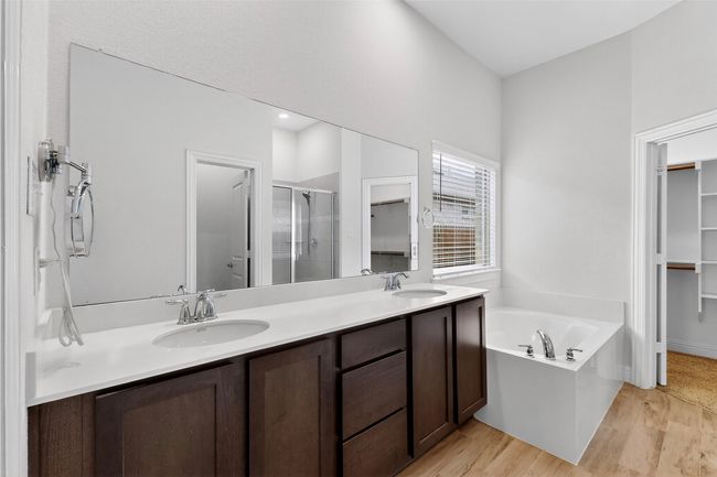 Bathroom with a stall shower, double vanity, wood finished floors, a bath, and a spacious closet | Image 19