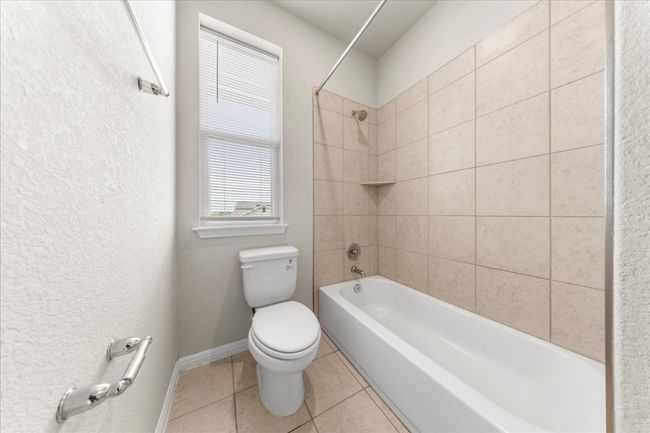 Bathroom featuring toilet, tile patterned floors, shower / bathtub combination, and baseboards | Image 30