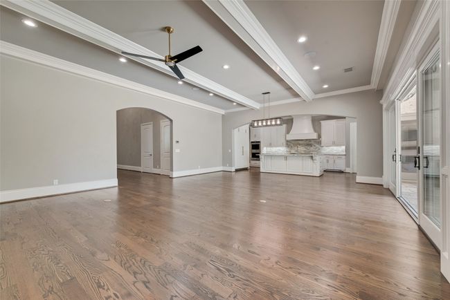 Unfurnished living room with arched walkways, baseboards, recessed lighting, beamed ceiling, and ceiling fan | Image 8