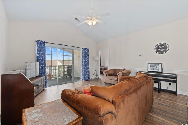 Living area with wood finished floors, a ceiling fan, and high vaulted ceiling | Image 10