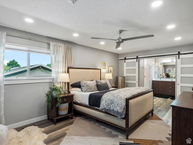 Bedroom featuring a barn door, recessed lighting, wood finished floors, and connected bathroom | Image 19