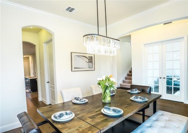 Dining space with a chandelier, dark wood-style floors, french doors, arched walkways, and ornamental molding | Image 5