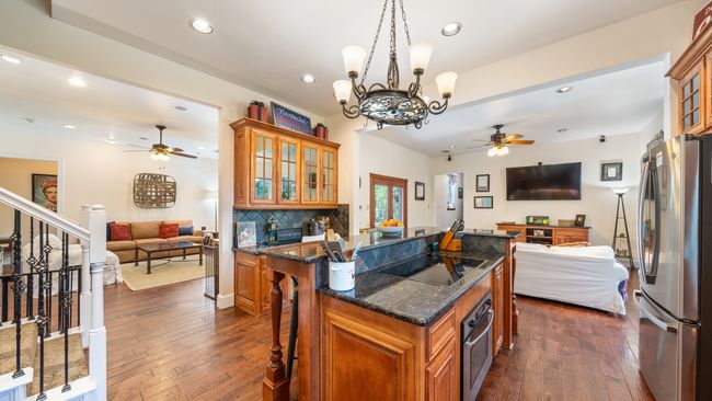 Kitchen with stainless steel appliances, brown cabinetry, ceiling fan with notable chandelier, and open floor plan | Image 9
