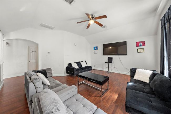 Located just off the entry, this spacious secondary living area offers impressive versatility—ideal as a formal sitting room, home office, media space, or lounge. Vaulted ceilings and natural light from the large front-facing window add openness, while neutral tones and updated flooring carry the home’s cohesive design throughout. | Image 6