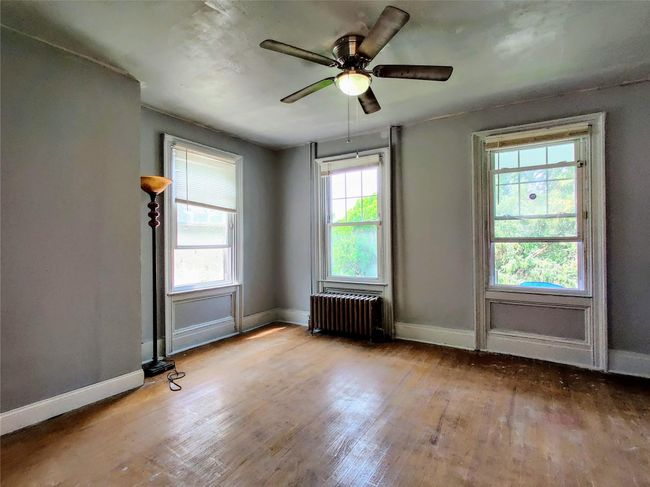 Spare room featuring baseboards, radiator, wood finished floors, and plenty of natural light | Image 16