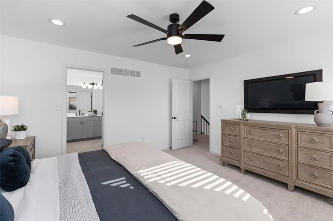 Bedroom with light carpet, connected bathroom, ceiling fan, and sink | Image 30
