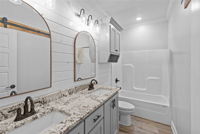 Full bath with ornamental molding, double vanity, wood finished floors, and shower / bathtub combination with curtain | Image 17