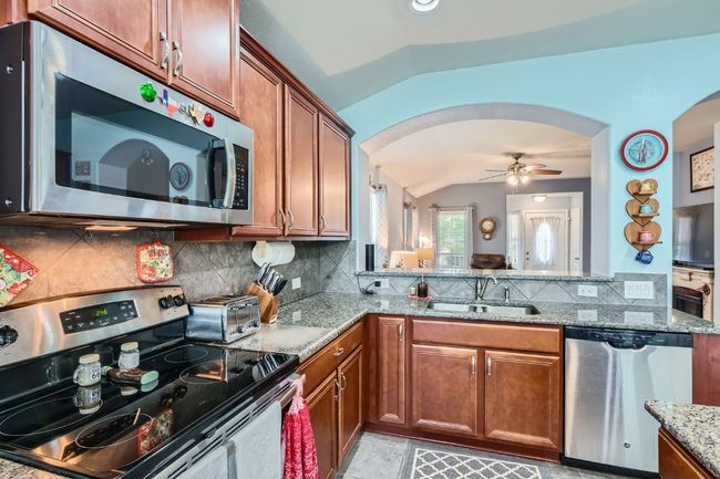 Kitchen with arched walkways, a sink, vaulted ceiling, decorative backsplash, and appliances with stainless steel finishes | Image 11