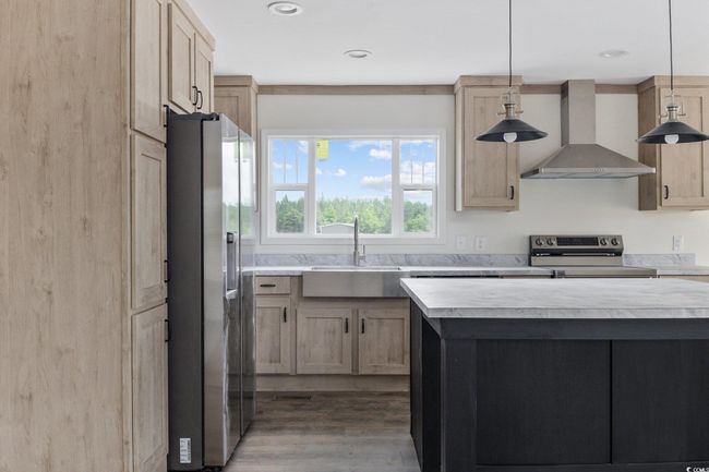 Kitchen with wall chimney exhaust hood, stainless steel appliances, light countertops, wood finished floors, and recessed lighting | Image 17