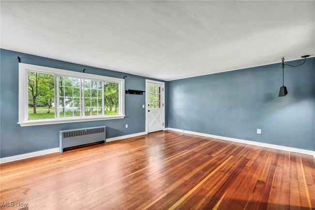 Unfurnished room with arched walkways, hardwood flooring, and a stone fireplace | Image 5