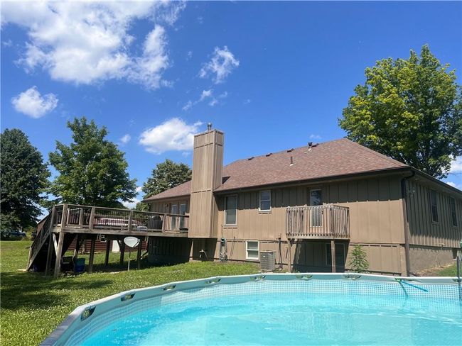 Outdoor pool featuring a wooden deck, a lawn, and stairs | Image 37