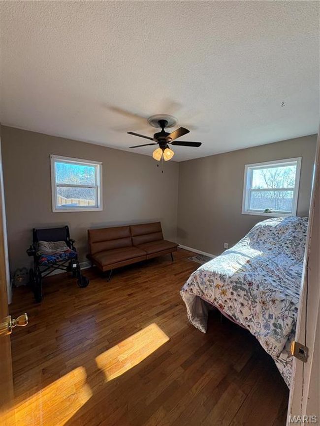 Bedroom featuring hardwood / wood-style flooring, ceiling fan, multiple windows, and a textured ceiling | Image 14