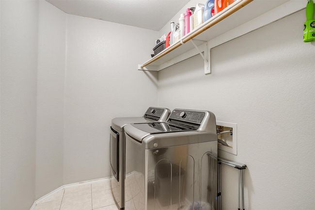 Laundry area with separate washer and dryer, light tile patterned flooring, and baseboards | Image 34