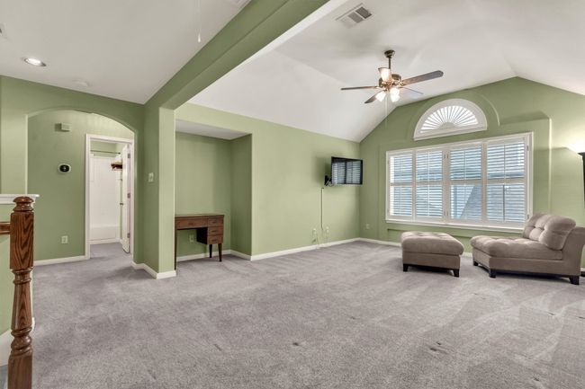 Living area with arched walkways, vaulted ceiling, visible vents, a ceiling fan, and carpet floors | Image 23
