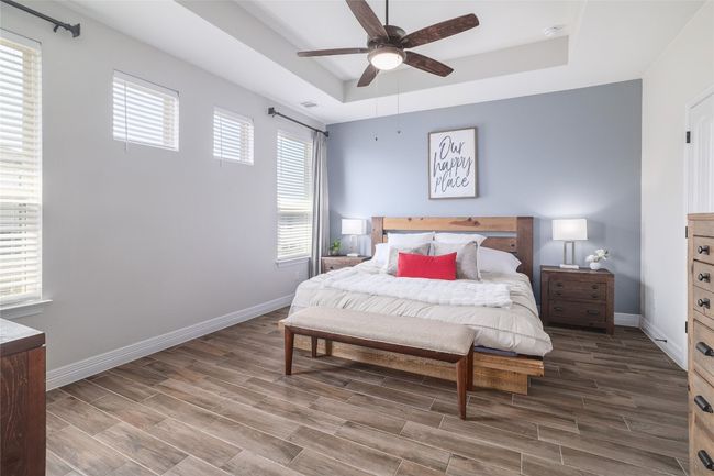 Bedroom featuring a raised ceiling, a ceiling fan, and wood finished floors | Image 18