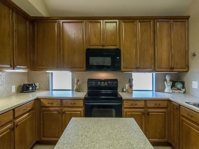 Another view of the kitchen counter workspace and windows allowing lots of light into the space. | Image 9