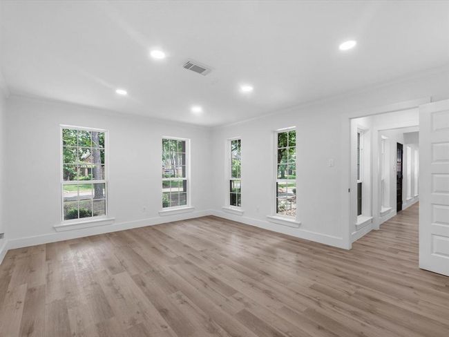 This photo shows a bright, spacious living area with large windows, light wood flooring, and recessed lighting, offering a modern and inviting atmosphere. | Image 20