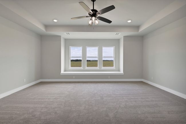 Carpeted empty room featuring a raised ceiling, a ceiling fan, and recessed lighting | Image 22