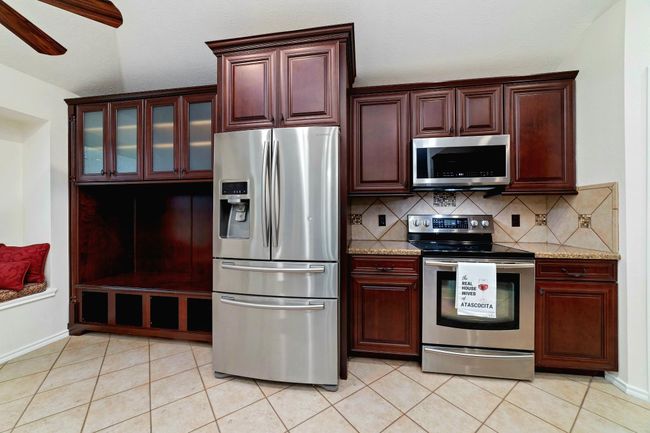 This kitchen anchors the home with its blend of comfort, function, and craftsmanship with inviting window seating in the breakfast area, custom cabinetry, a sleek stainless-steel fridge and range, and so much more. | Image 13