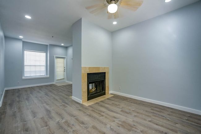 Unfurnished living room featuring a fireplace, wood finished floors, a ceiling fan, and recessed lighting | Image 10