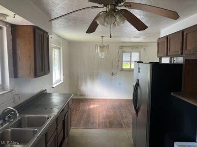 Kitchen with sink, ceiling fan with notable chandelier, a textured ceiling, light hardwood / wood-style floors, and stainless steel refrigerator with ice dispenser | Image 3