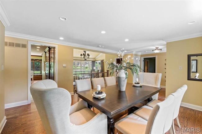 Dining area with crown molding, wood finished floors, a chandelier, and recessed lighting | Image 11