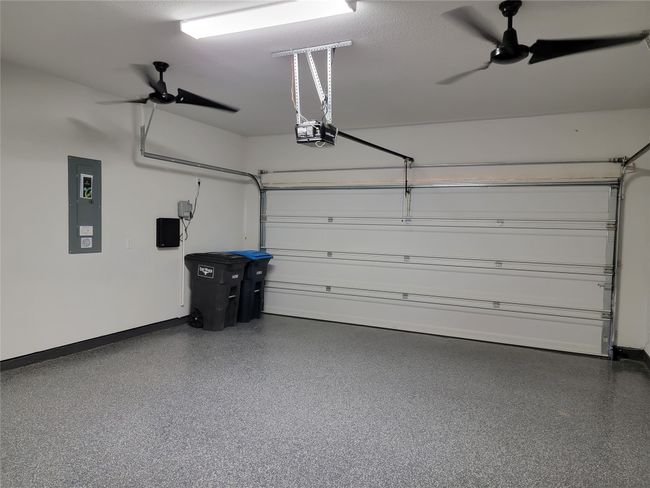 Garage with a garage door opener, a ceiling fan, electric panel, and baseboards | Image 25