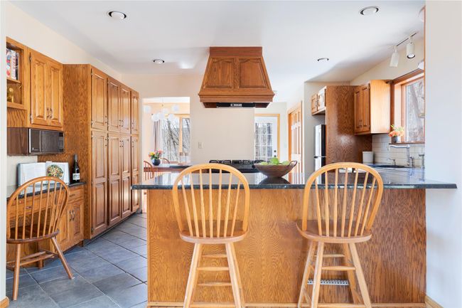 Kitchen featuring dark countertops, tasteful backsplash, a sink, custom range hood, and freestanding refrigerator | Image 11