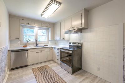 Kitchen with tile walls, stainless steel appliances, sink, and light hardwood / wood-style floors | Image 3