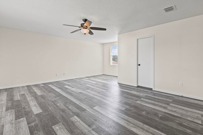 Empty room with ceiling fan, wood finished floors, and a textured ceiling | Image 15