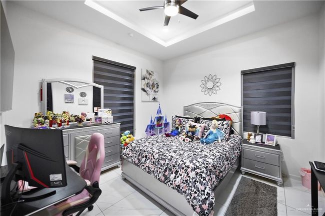 Bedroom with a raised ceiling, a ceiling fan, and light marble finish floors | Image 12