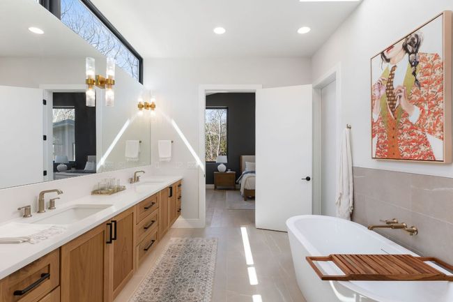 Ensuite bathroom featuring double vanity, connected bathroom, a freestanding bath, and a sink | Image 5