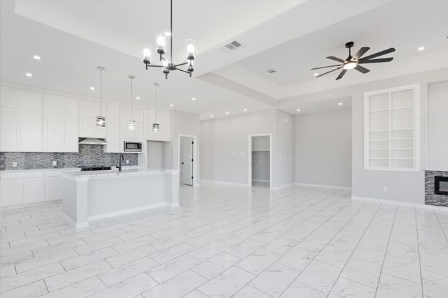 Kitchen featuring open floor plan, stainless steel microwave, light countertops, white cabinets, and a chandelier | Image 16