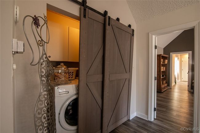 Washroom with dark wood-type flooring, a barn door, cabinet space, baseboards, and washer / dryer | Image 23