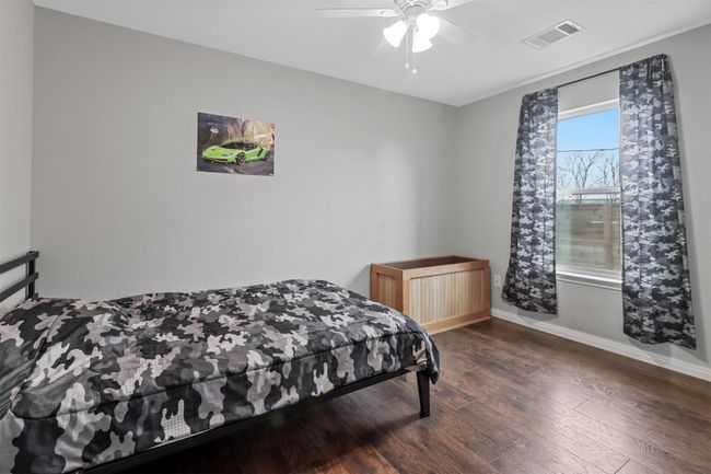 Bedroom with wood finished floors, baseboards, ceiling fan, and visible vents | Image 25