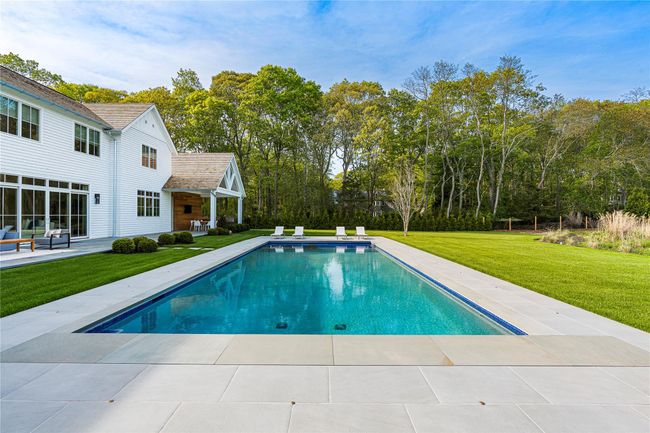 Swimming pool featuring a patio, a yard, and view of scattered trees | Image 45