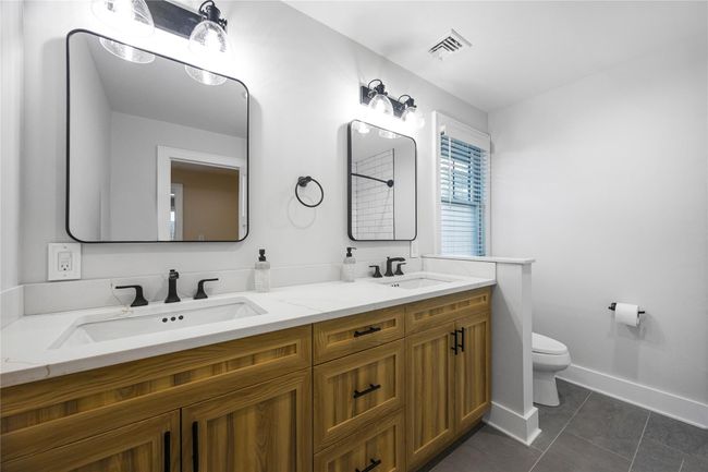 Bathroom featuring tile patterned floors, visible vents, toilet, and a sink | Image 36