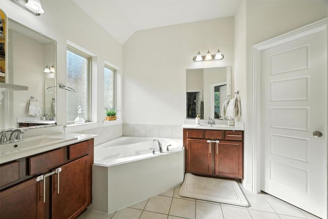 Full bathroom featuring tile patterned flooring, lofted ceiling, two vanities, and a bath | Image 20