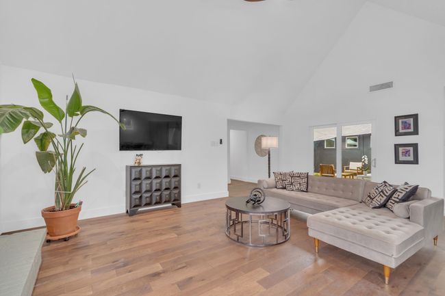 Living room with high vaulted ceiling, baseboards, wood finished floors, and visible vents | Image 10