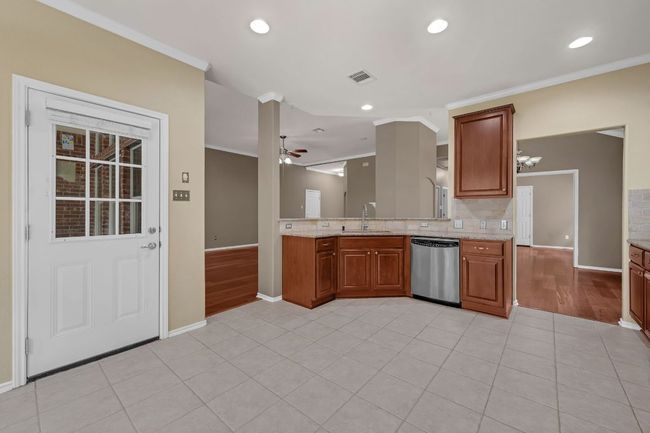 . The open-concept kitchen is a chef’s dream, offering granite countertops, stainless steel appliances, recessed lighting, cherry cabinetry with pull-out shelves, and a convenient breakfast bar overlooking the living room. | Image 11