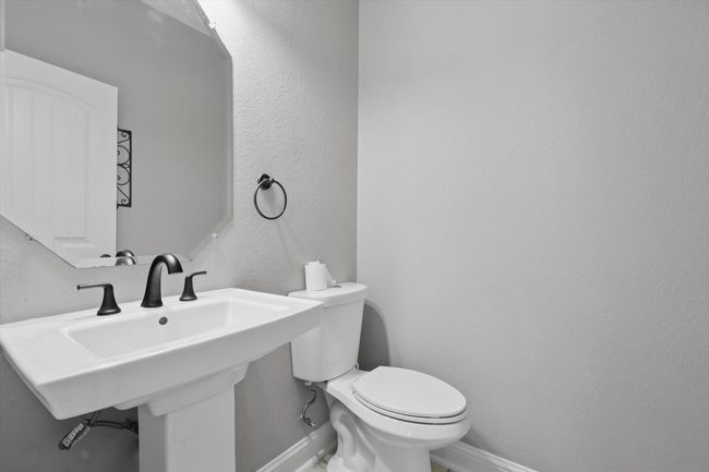 Half bathroom with baseboards, toilet, a sink, and a textured wall | Image 16