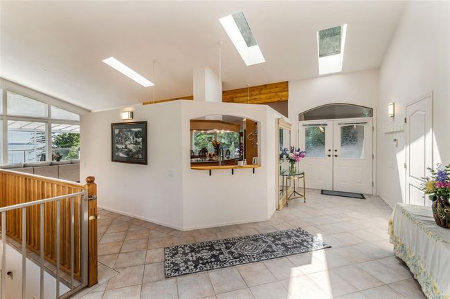 Foyer with a skylight, tile patterned flooring, beamed ceiling, baseboards, and high vaulted ceiling | Image 9