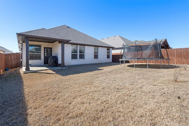 Rear view of house featuring a trampoline, a fenced backyard, brick siding, and a shingled roof | Image 27