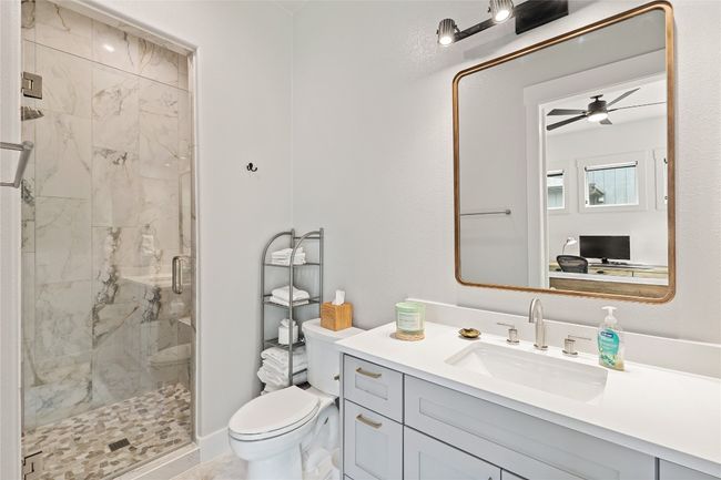 Full bathroom featuring toilet, a marble finish shower, vanity, and ceiling fan | Image 22