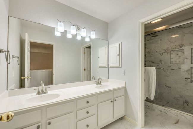 Full bath featuring marble look tiles, a marble finish shower, and double vanity | Image 31