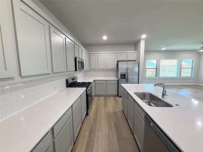 Kitchen with stainless steel appliances, a sink, gray cabinets, light wood-style flooring, and recessed lighting | Image 13