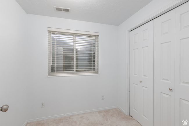 Unfurnished bedroom with a closet, light carpet, and baseboards | Image 18