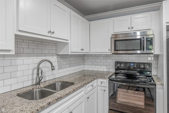 Kitchen featuring stainless steel microwave, a sink, white cabinets, and black range with electric cooktop | Image 5