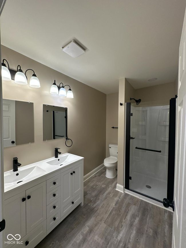 Unit 2 - Hall bathroom with wood finished floors, a shower stall, and double vanity | Image 21