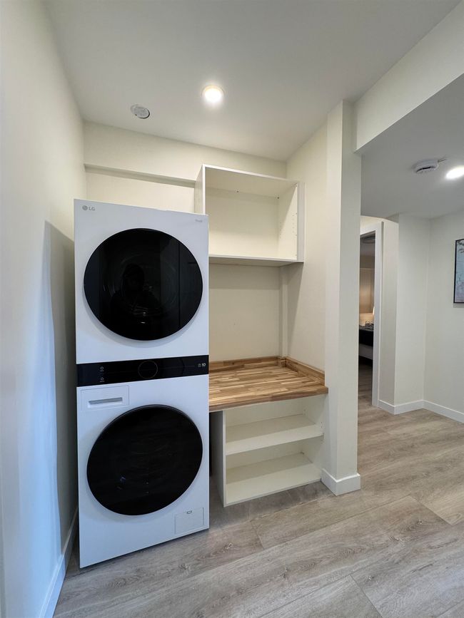 Washroom featuring stacked washer / drying machine and wood finished floors | Image 30